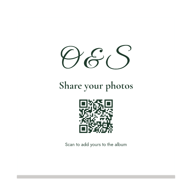 A white cocktail napkin with the couple's monogram and a QR code in forest green